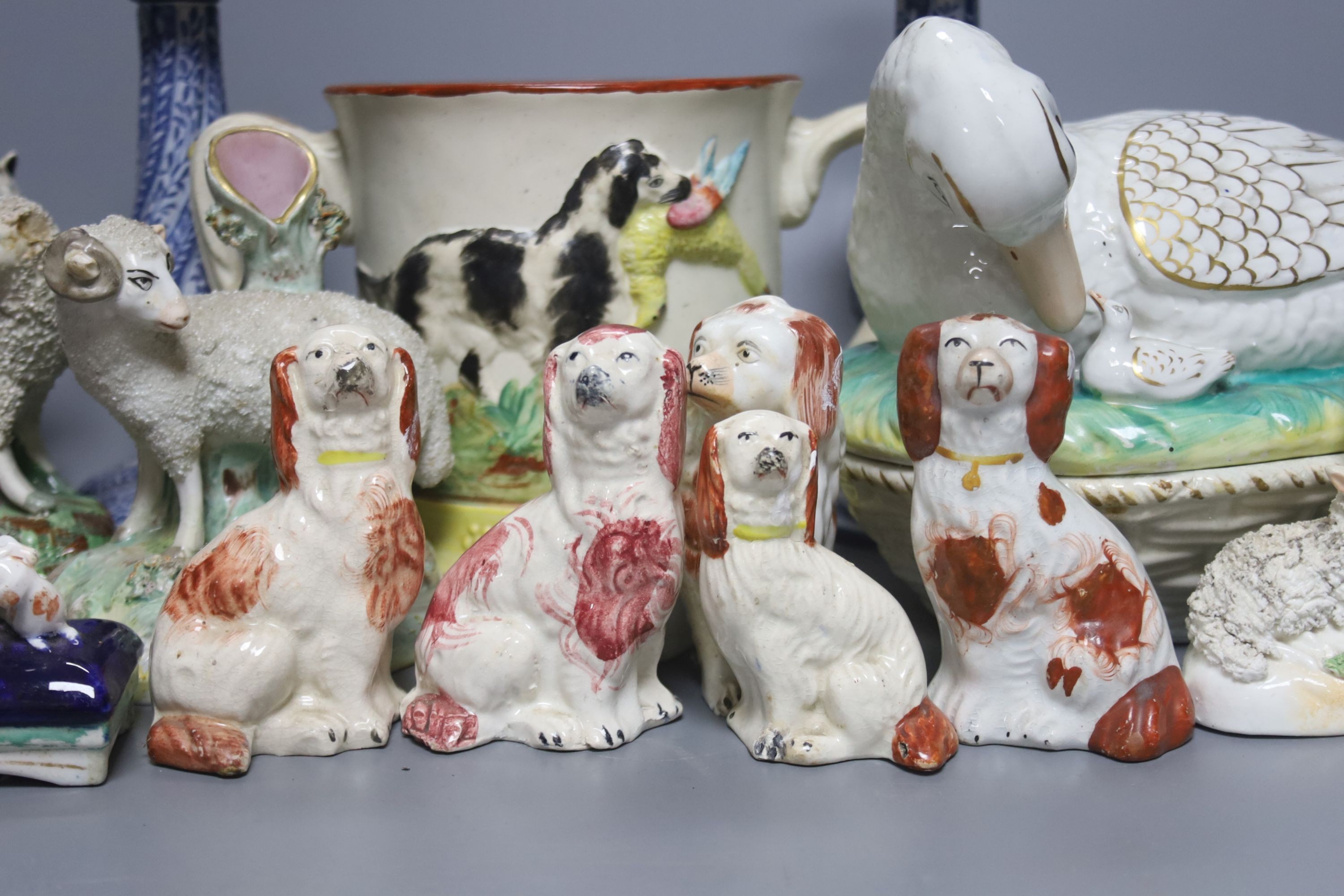 A Staffordshire pottery ‘duck’ tureen and cover, 23cm, a pair of faience candlesticks, Staffordshire figures of dogs, sheep and a zebra and a two handled loving mug